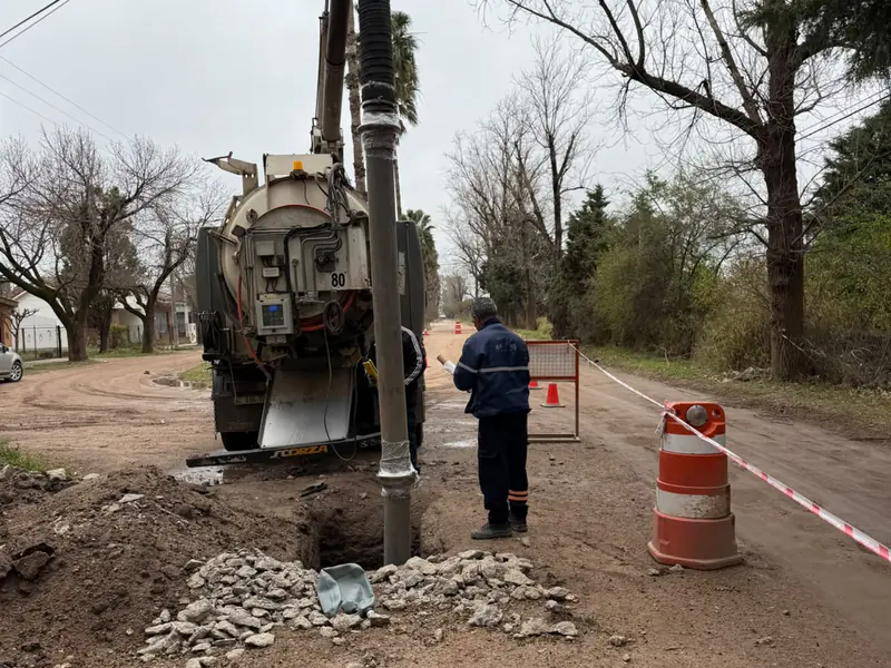 Equipo hidrojet con el tubo de succión en una excavación de calle de tierra, con un operario al lado