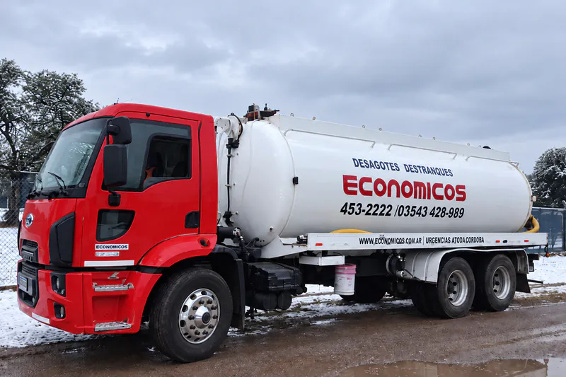 Camión atmosférico de Económicos con cabina roja y tanque blanco, en un predio con nieve